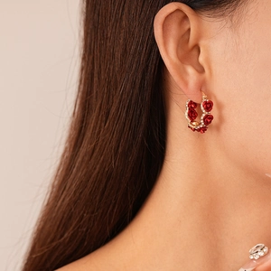 Detail of red rose earrings with gold plating and sparkling diamonds on a model