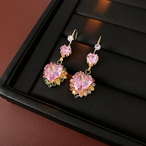 Detail of gold heart earrings with pink gemstones and colorful zircon in a tray
