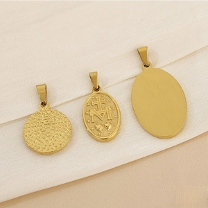 Detail of vintage gold religious pendants with hammer texture on a beige satin background