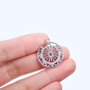 Détail du pendentif rond argenté à motif d'étoile montré sur les doigts pour la taille