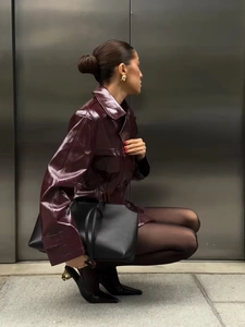 Stile street di una giacca in pelle lucida bordeaux intenso abbinata a borsa tote nera