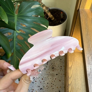 Macro view of pink marble acetate hair claw clip showing smooth texture and teeth