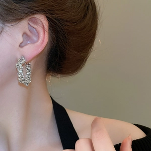 Close-up of U-shaped silver earrings with sparkling rhinestones worn by a model