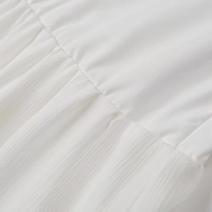 Close-up of white pleated fabric texture and fine stitching on a summer maxi dress
