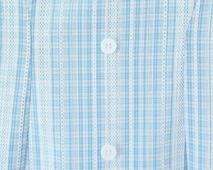 Detail of blue and white plaid fabric with delicate lace trim and white buttons