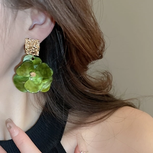 Gros plan d'une boucle d'oreille fleur en acrylique vert avec métal doré sur un mannequin