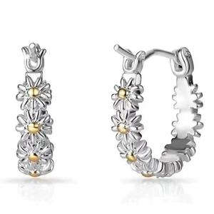 Detailed close-up of two-tone daisy earrings with silver petals and a golden center