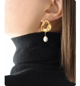 Detail of model wearing 18K gold plated lava earrings with freshwater pearl drop pendants
