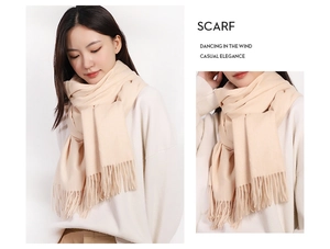 Close-up of beige cashmere-feel scarf with soft fringe detail and model styling