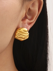Detail of vintage wavy texture and irregular oval design on high-quality gold earrings