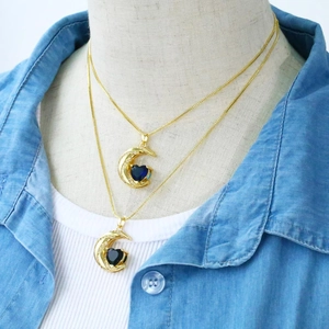Detailed close-up of crescent moon heart necklaces with blue and black zircon stones
