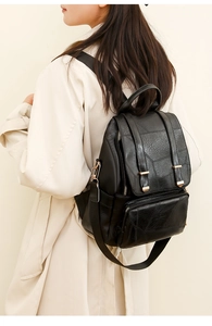 Detailansicht eines schwarzen Rucksacks mit geometrischen Nähten, getragen zum beigen Mantel
