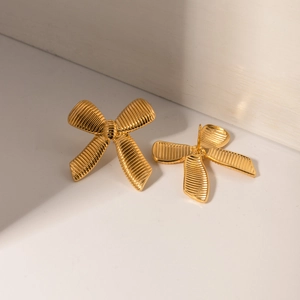 Macro detail of 18k gold plated stainless steel bow earrings with striped ribbon texture