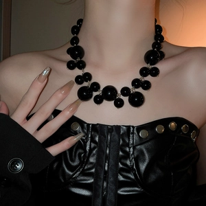 Macro shot of an oversized black bead necklace with irregular clusters and retro gothic style