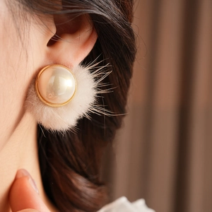 Close-up of pearl earrings with golden trim and white fluffy fur detail for women