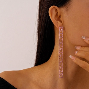 Close-up of pink rhinestone long tassel geometric Greek fret earrings on model