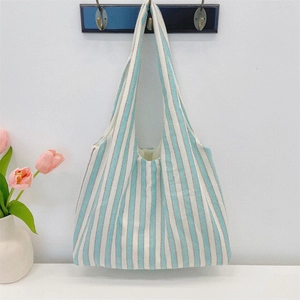 Close-up of minimalist blue striped canvas tote bag hanging in a bright interior setting