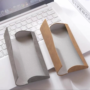 Foldable nubuck leather sunglasses case in brown and grey colors on a white laptop