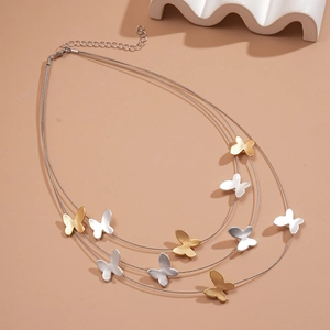 Three-layer butterfly choker necklace with gold and silver matte pendants on brown background