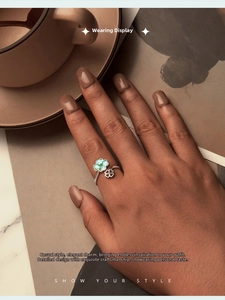 Close-up of S925 silver clover ring with enamel detail on finger with lifestyle backdrop