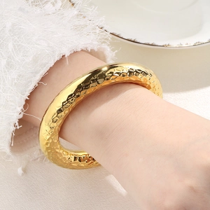 Detail of 18k gold hollow stainless steel bangle with hammered texture on female wrist