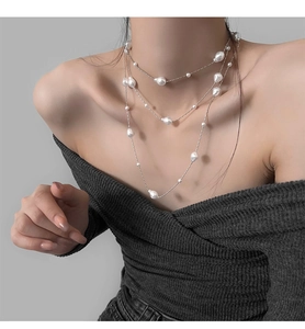 Detail of a layered long necklace featuring irregular baroque pearls on silver chains