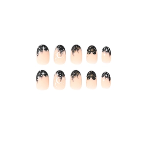 Press-on nails in matte black and nude French style with white moon and gold stars
