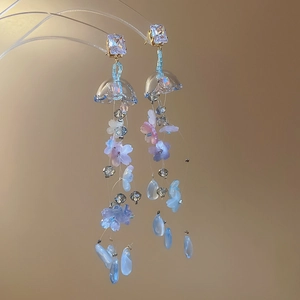 Detail of floral tassel earrings with purple resin petals and crystal studs