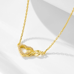 Macro view of gold infinity heart necklace pendant with pavé cubic zirconia inlay