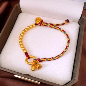 Detail of woven bracelet with gold lotus charms and Fu character inscription