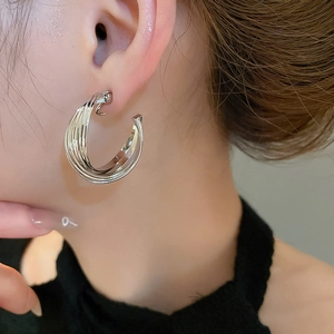Macro detail of silver twisted C-shaped earrings with a polished metallic finish