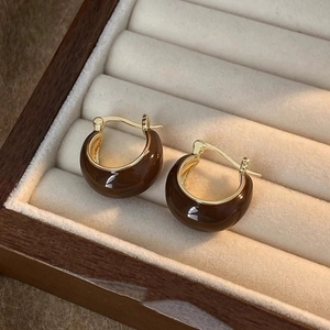 Detailed view of brown beaded hoop earrings with gold accents on a wooden jewelry display box