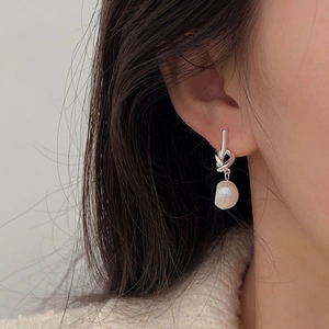 Detail of a 925 sterling silver knot earring with a single pearl on a model's ear