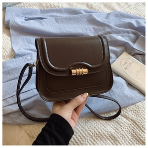 Détail d'un sac besace marron foncé avec fermoir rotatif rétro doré et bandoulière fine