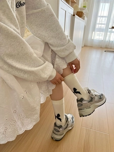 Detail of white cotton crew socks with black bow pattern and feminine lace edge
