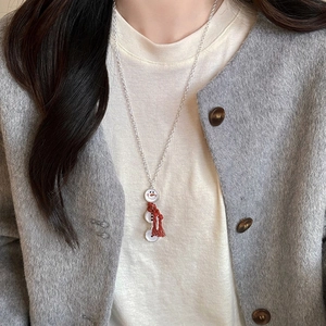 Détail d'un collier pendentif bonhomme de neige avec écharpe rouge à pompons
