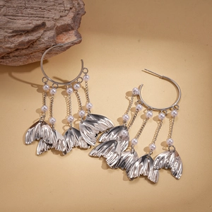 Silver fish tail tassel earrings with faux pearls on beige textured background