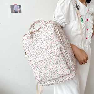Close-up of floral school backpack featuring pink flower patterns and front zipper pocket