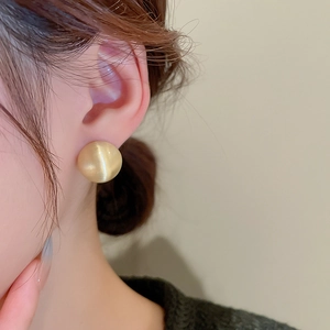 Macro close-up of a golden brushed hemispherical stud earring with elegant cat eye luster