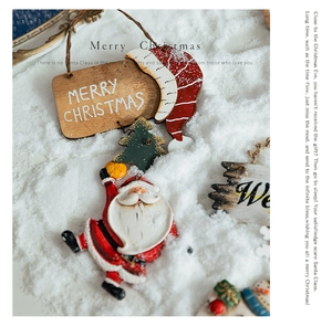Close-up of Santa resin ornament and wooden Merry Christmas sign on snow background