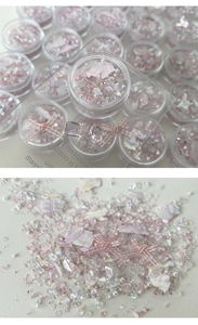 Macro shot of K9 crystal nail art set with pink bows, pearls and iridescent shell flakes