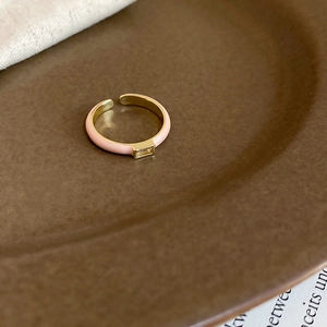 Detail of pink enamel ring with yellow rectangular zircon on textured ceramic plate