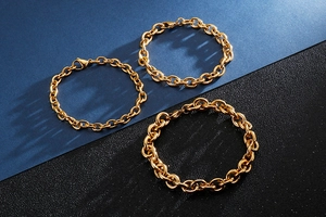 Three gold stainless steel paperclip chains in different thicknesses on a dark background