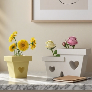 Minimalist heart cutout ceramic flower pots with daisies and roses on marble tabletop
