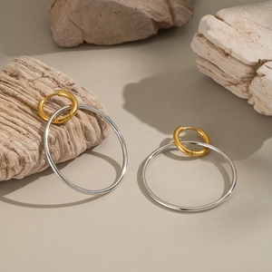 Nahaufnahme ineinandergreifender Gold- und Silberringe auf Naturstein für modernen Look