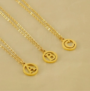 Vue macro de colliers en acier inoxydable doré 18 carats avec pendentifs lettres A, B, C