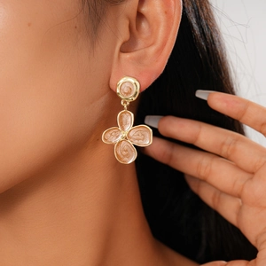 Detail of floral enamel earrings with golden frame on model for elegant resort style