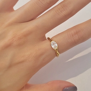 Detail of irregular gold ring featuring an oval zircon stone on a woman's finger
