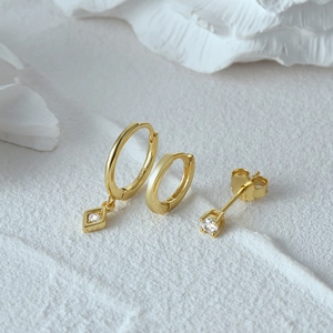Detailed macro view of three 925 silver gold-plated earrings with diamond accents