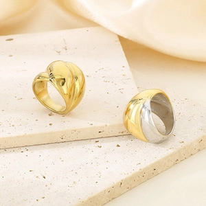 Macro view of wide curved stainless steel rings in gold and two-tone finishes